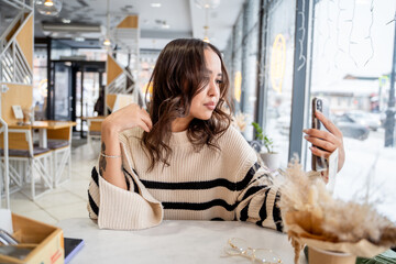 Young woman sitting in cafe and talking on video call