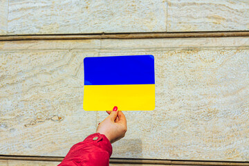 A hand with Ukrainian flag on a beige background. Support Ukraine. 