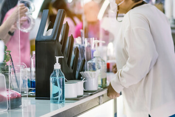 Blue alcohol gel bottle for hand cleaning to prevent the spreading of the Coronavirus (Covid-19) on counter to service for customers at cafe or coffee shop. Healthcare concept. New normal lifestyle.