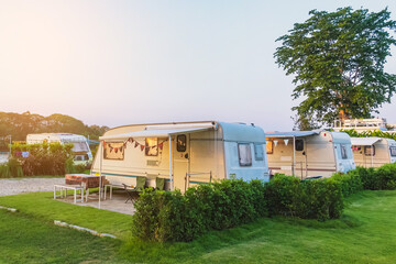 Cozy retro travel trailer Caravan on green grass before sunset near riverside in peaceful...