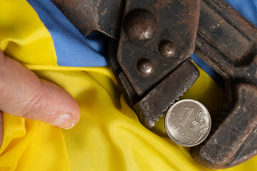 The gas key holds the Russian ruble on the background of the flag of Ukraine in the hands of the...