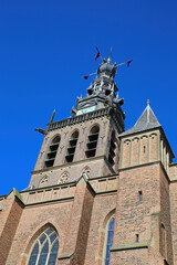 Fototapeta premium Nijmegen (Stevenskerk), Netherlands - February 27. 2022: Low angle view on church bell tower against deep blue sky
