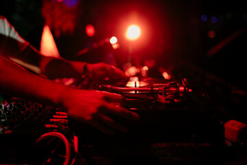 Close view of the hands of a disc jockey mixing a vinyl records during a performs in a music festival