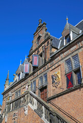 Nijmegen, Netherlands - February 27. 2022: Low angle view on medieval renaissance red brick style facade against cloudless blue sky 