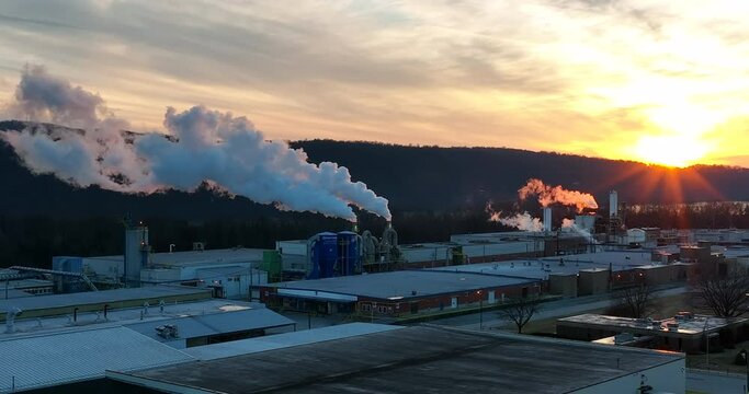 Air quality, environmental pollution. Climate change and global warming concept in warm sunshine. Factory plant manufacturing in USA at winter sunset. Aerial.