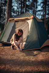 An Asian woman is pitching a tent in the pine tree forest at Pang Oung, Mae Hong Son province, Thailand.