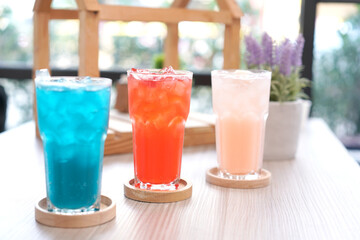 Refreshing cold beverage for summer on ice. Colorful summer drink in tall glass with wood saucer for hot day and party.