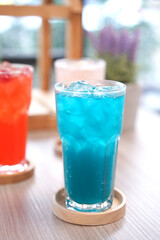 Refreshing cold beverage for summer on ice. Colorful summer drink in tall glass with wood saucer for hot day and party.