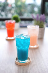 Fototapeta premium Refreshing cold beverage for summer on ice. Colorful summer drink in tall glass with wood saucer for hot day and party.