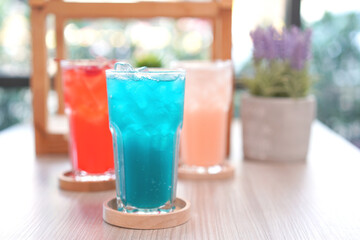 Refreshing cold beverage for summer on ice. Colorful summer drink in tall glass with wood saucer for hot day and party.