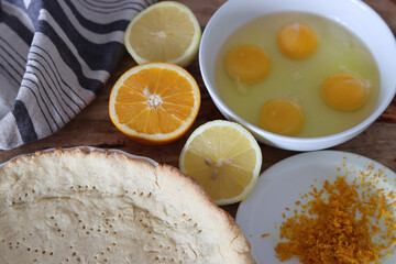 Making orange pie. Close up photo of fresh ingredients. Crusty dough, oranges, sugar, eggs top view photo. 