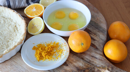 Making orange pie. Close up photo of fresh ingredients. Crusty dough, oranges, sugar, eggs top view photo. 