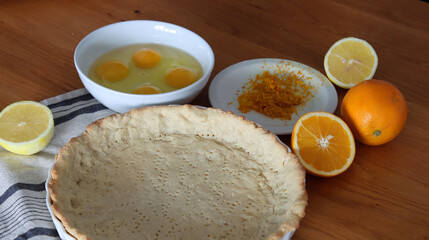 Making orange pie. Close up photo of fresh ingredients. Crusty dough, oranges, sugar, eggs top view photo. 