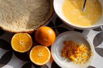 Making orange pie. Close up photo of fresh ingredients. Crusty dough, oranges, sugar, eggs top view photo. 