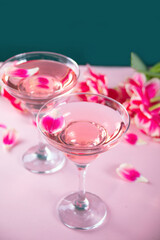 Glasses of pink cocktail with flowers and petals. Birthday party or Valentines day romatic couple concept.
