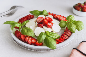 Summer Caprese salad with strawberries. Strawberry salad with basil and mozzarella. Healthy eating concept. Italian cuisine