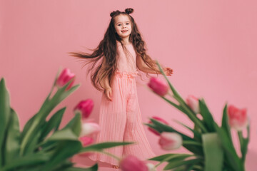 Obraz na płótnie Canvas Portrait of a girl with tulips on pink background.