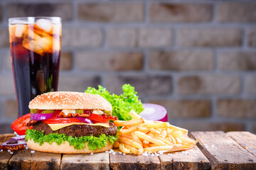 Hamburger with french fries and soft drink with ice on wooden table