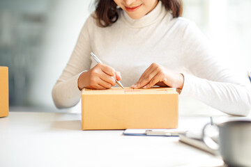 Startup SME small business entrepreneur SME or freelance Asian woman using a laptop with box, Young success Asian woman with her hand lift up, online marketing packaging box and delivery, SME concept.