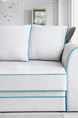 Modern white sofa with decorative pillows. Beautiful trendy interior. Vertical photography.