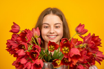 Obraz na płótnie Canvas happy teen girl hold spring tulip flowers on yellow background