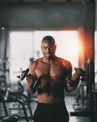 Fototapeta na wymiar African sport man using dumbbell exercise at gym. Asian body building for muscle training. Sport health gym concept