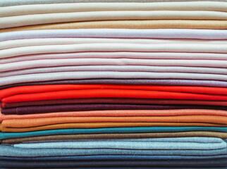 Rainbow clothes background. Pile of bright folded clothes.