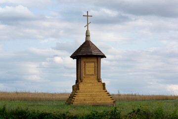 Wooden field cross at the crossroads in the field.