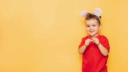 Studio portrait of a Caucasian boy in a mouse costume on a bright yellow background, with a place for your text or advertising