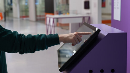 Close-up of a woman using a touch screen information booth.