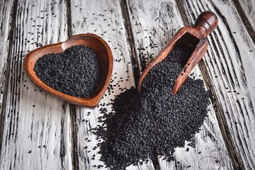 Seeds and a healthy lifestyle. Black cumin seeds on a wooden table.