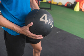 A young man holding a 4 kg medicine ball. Doing cross training or other high intensity workout at...