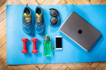 Sports shoes and fitness equipment. Fitness equipment and a laptop. Fitness at home. Top view.