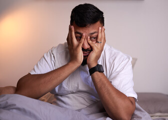 An adult man covers his face struggling to wake up in the early morning