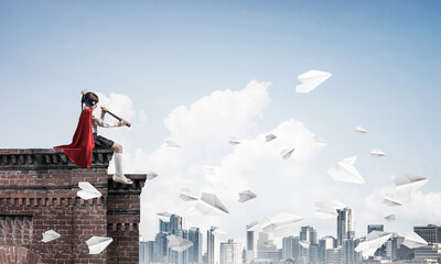 Girl power concept with cute kid guardian against cityscape background. Mixed media