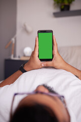 An unidentified man holds a mobile phone in his bedroom. Chroma key