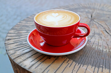 A Hot Cappuccino Coffee in Red Cup Served on Tree Stump Table