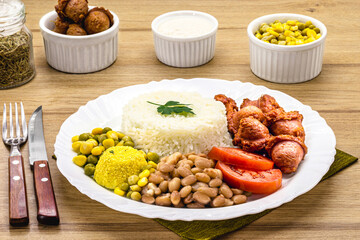 plate of rice and beans typical of Brazil, fried sausage, fried egg, chopped vegetables and salad