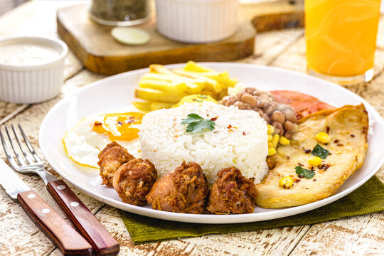 plate of rice and beans typical of Brazil, fried sausage, fried egg, chopped vegetables and salad