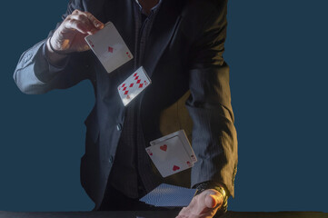 A man in a suit juggles playing cards. The croupier shuffles playing cards. Dark room for playing...
