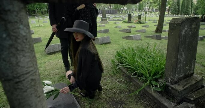 Relatives lay flowers on the grave of the deceased, griving at the cemetery, 4k 60p Prores