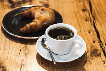 White cup of filter coffee stands on a wooden table