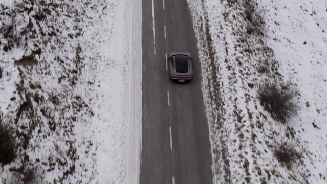 Car in the mountains of the Caucasus in winter. An electric car drives through winter landscapes. Flights on the copter, tracking the car from the side to the rear and three-quarters. General plans.