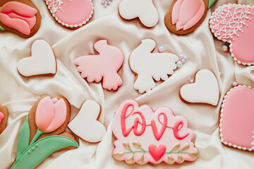background banner greeting card for international women day or valentines day with white heart love, tulips and pigeon shape gingerbread cookies on white silk fabric background