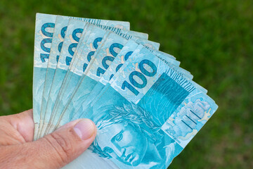 brazilian money in hand with green background