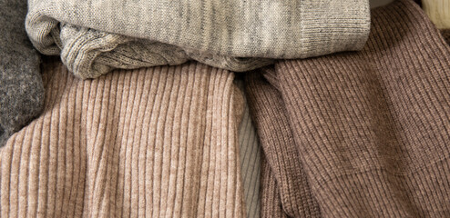 Pile of knitted warm sweaters clothes close up