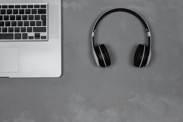 Layout of a laptop with stereo headphones on a gray background.