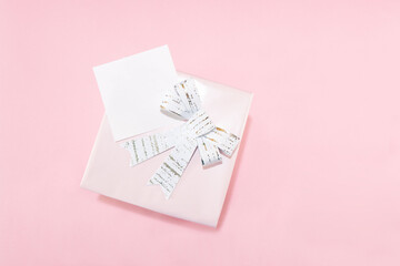 General shot, pink background composition with gift and white ribbon for Mother's Day or Women's Day. On the gift a white label for text.