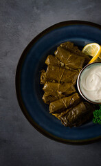 Dolma, cabbage rolls, grape leaves with filling, white sauce, lemon and herbs, rustic, selective focus, no people,