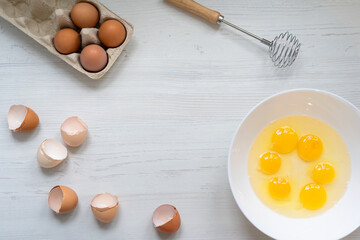 cooking process, eggs in a white bowl on the kitchen table, flat view, breakfast concept
